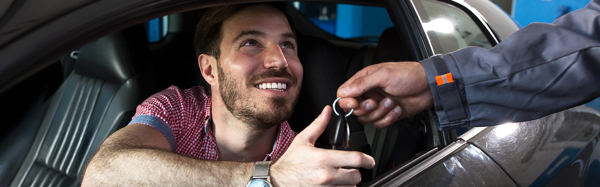 customer in car getting keys from salesman